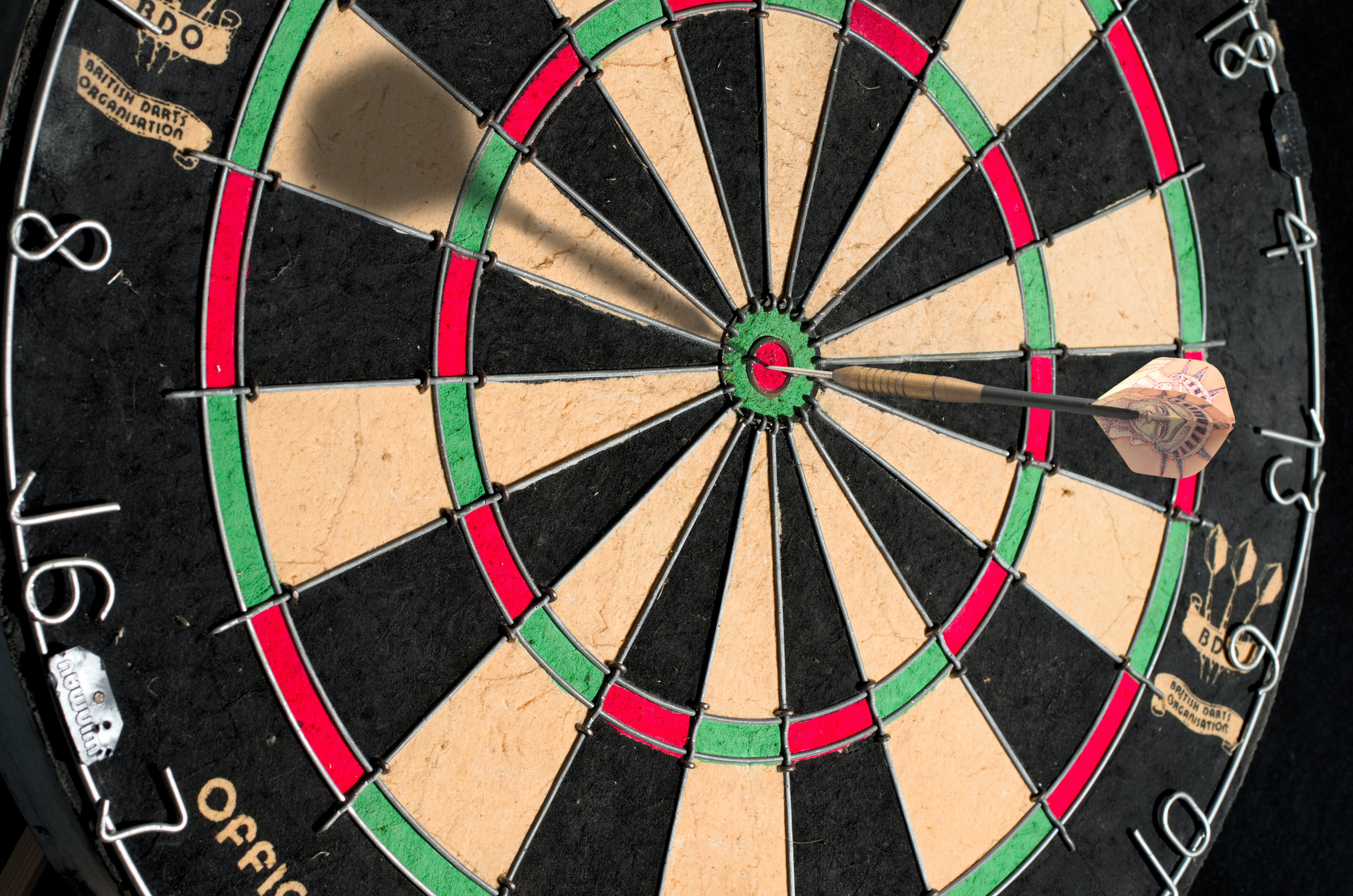 Close up of a dartboard with a dart in the bullseye