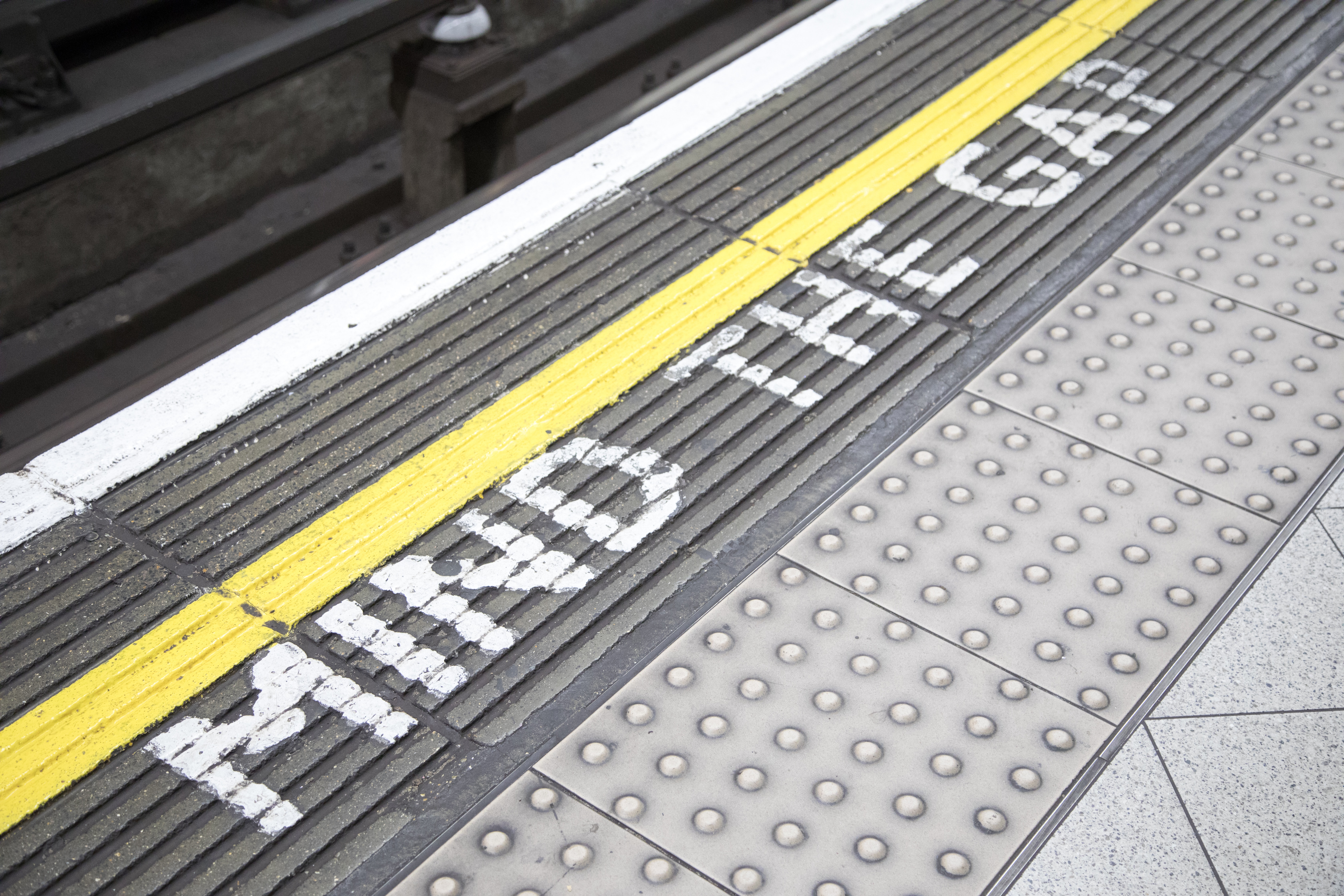 Close up of 'mind the gap' marking along the edge of a train platform