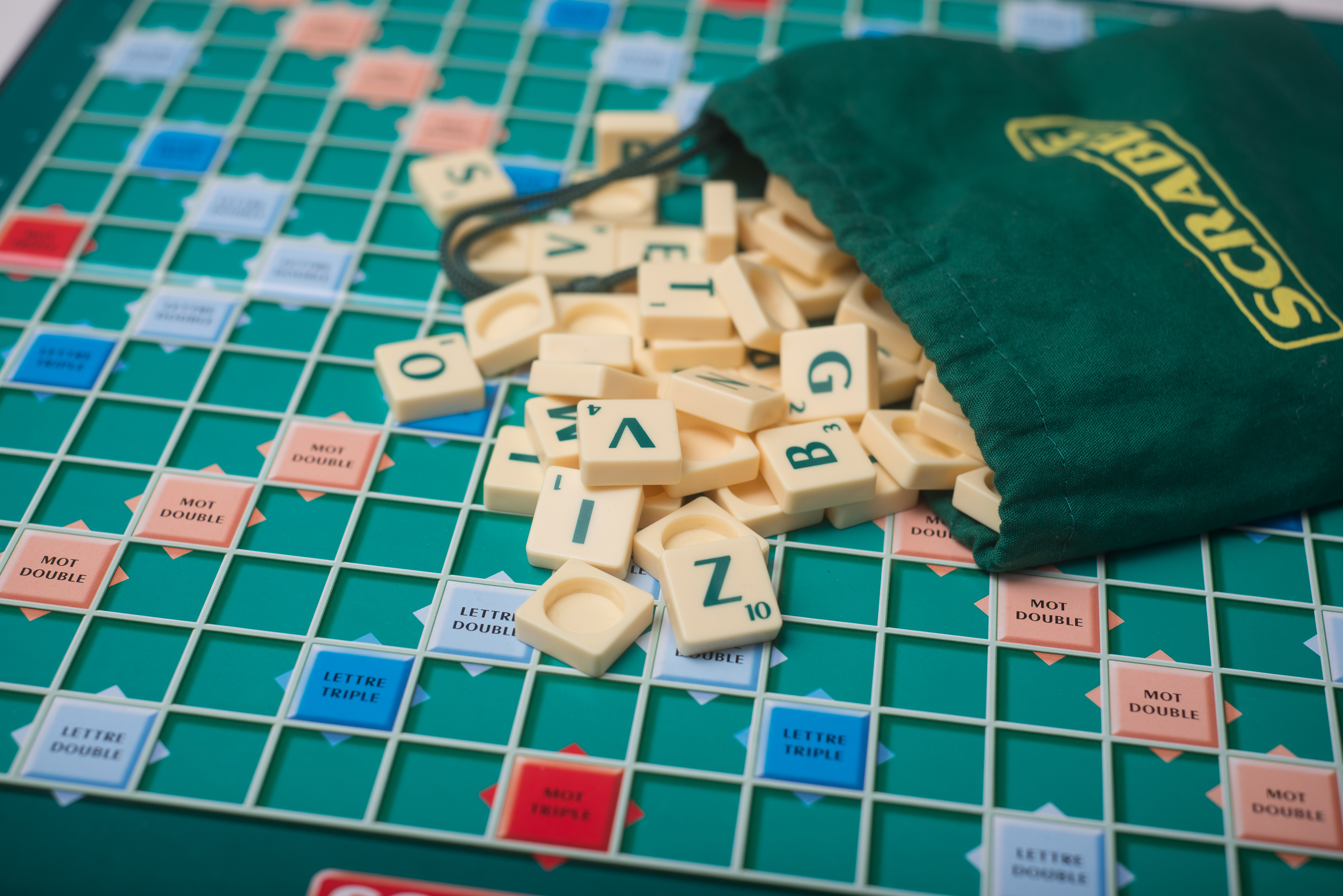 Closeup of plastic letters of Scrabble game fallen from bag on boardgame
